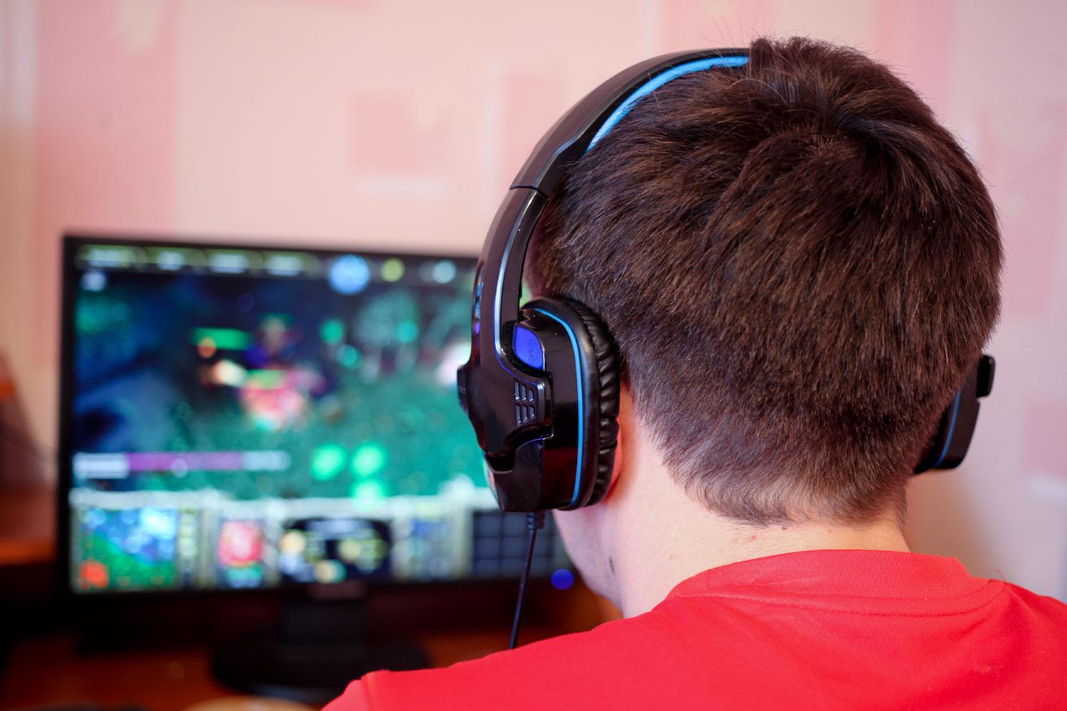 Man wearing headphones and looking at monitor.