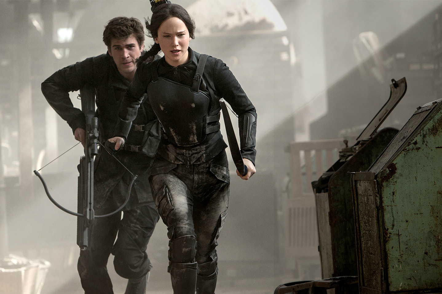 A man and woman run toward a fight in Mockingjay.