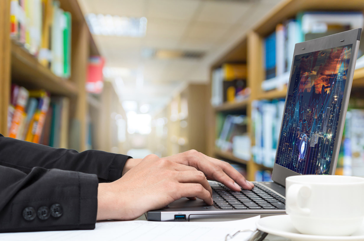 Man in suit jacket using computer in library.