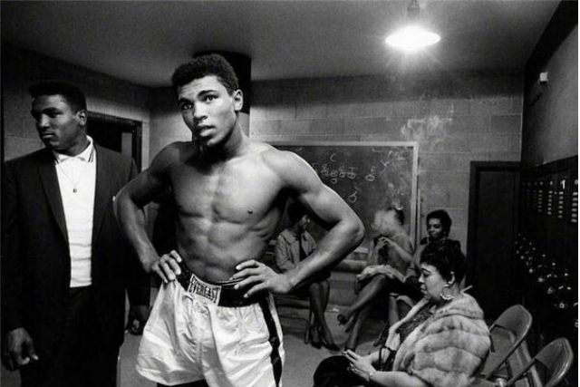 Muhammad Ali stands with his hands on his hips.