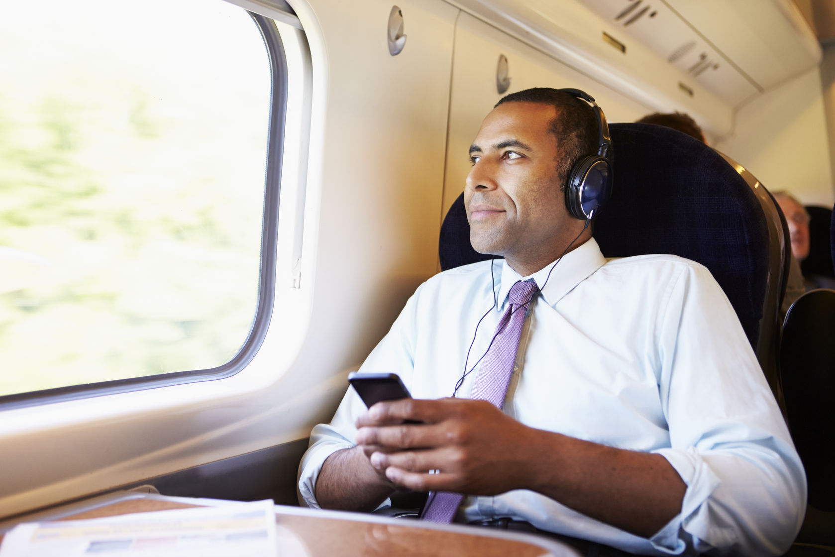 iheartmedia launches two new streaming services 28159403  businessman relaxing on train listening to music