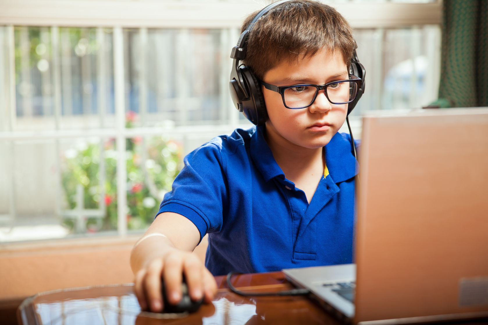 digital divide smartphones dont help young boy working on computer with headphones and mouse