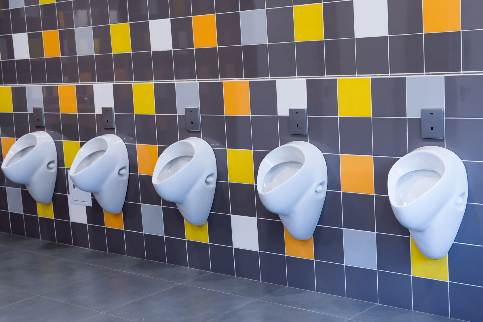 splashproof urinal research 40640071  white porcelain urinals against a yellow and orange tiled wall