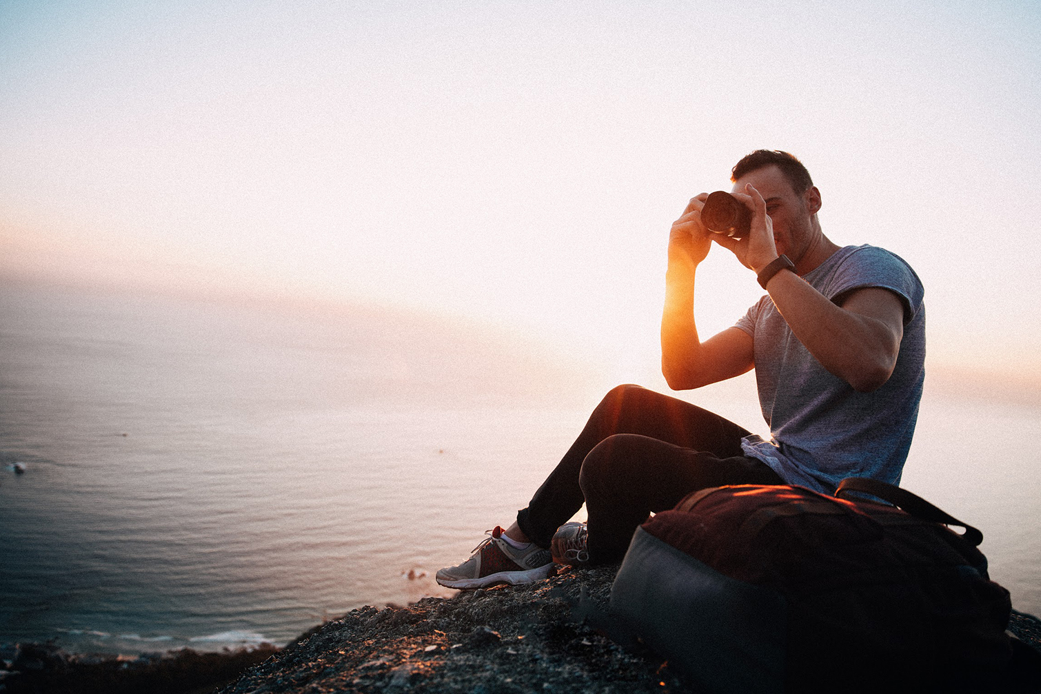 videoblocks is now storyblocks graphicstock young male adult taking photos with camera while sitting on edge of mountain beau