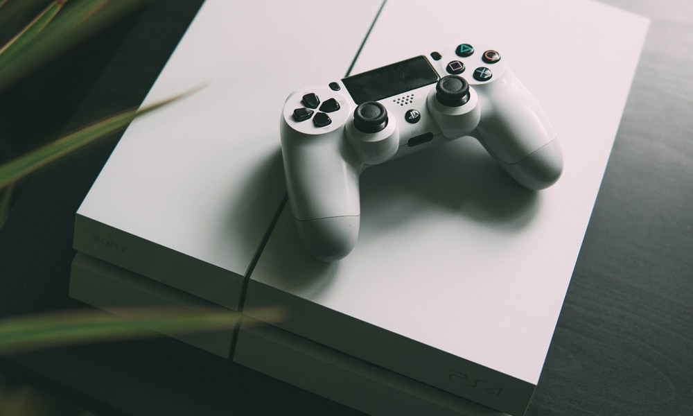 White PS4 under white DualShock 4 controller.