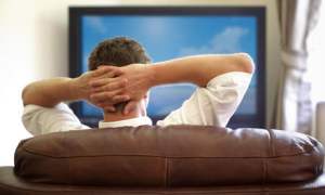 sling tv expands spanish language programming 25151395 man sitting on a sofa watching with hands folded behind his head jpg