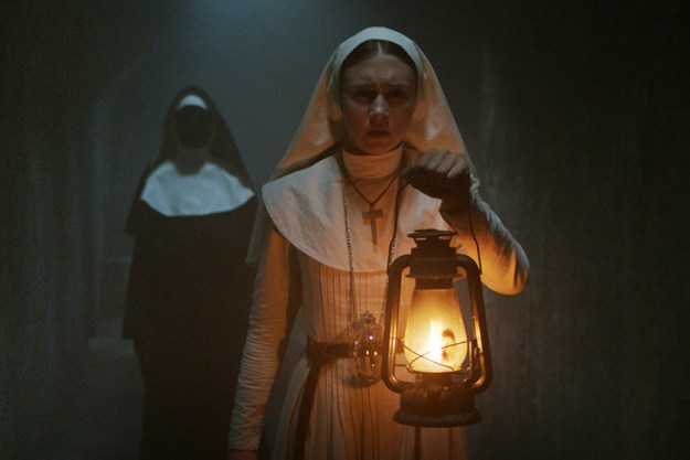Taissa Farmiga as Sister Irene holding a lantern while Valak the demon nun stands behind her in The Nun.