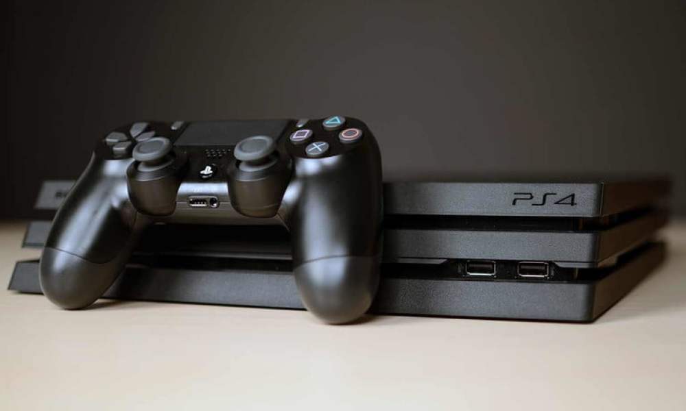 A PS4 Pro sitting on a table with a controller.