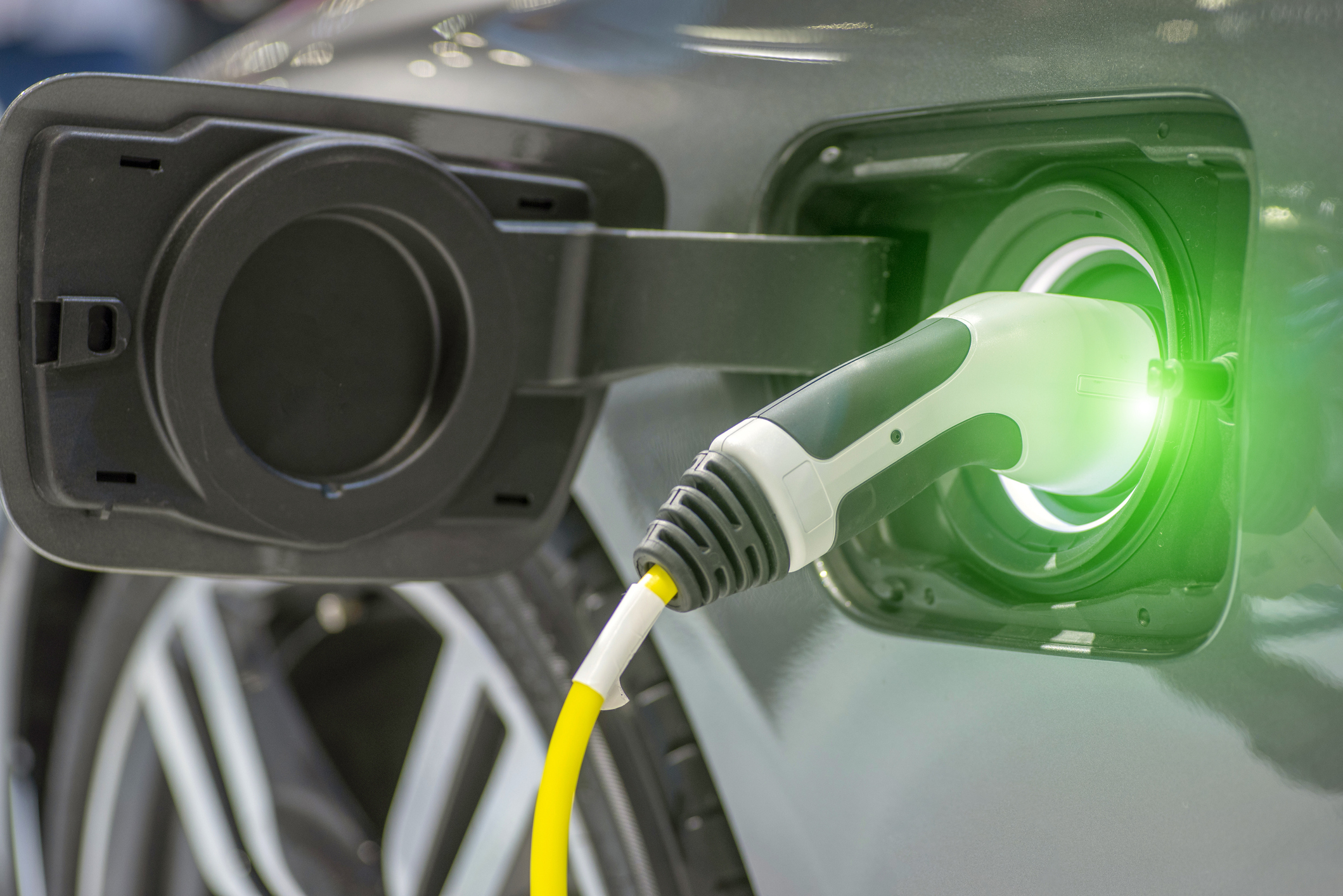 Close up of the Hybrid car electric charger station with power supply plugged into an electric car being charged.