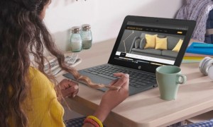 A woman in a yellow jumper sits at a desk with an HP Chromebook 11.6 open in front of her, and a mug alongside.