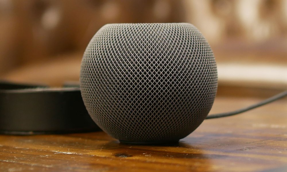 Black HomePod mini on a side table, in front of an Apple TV