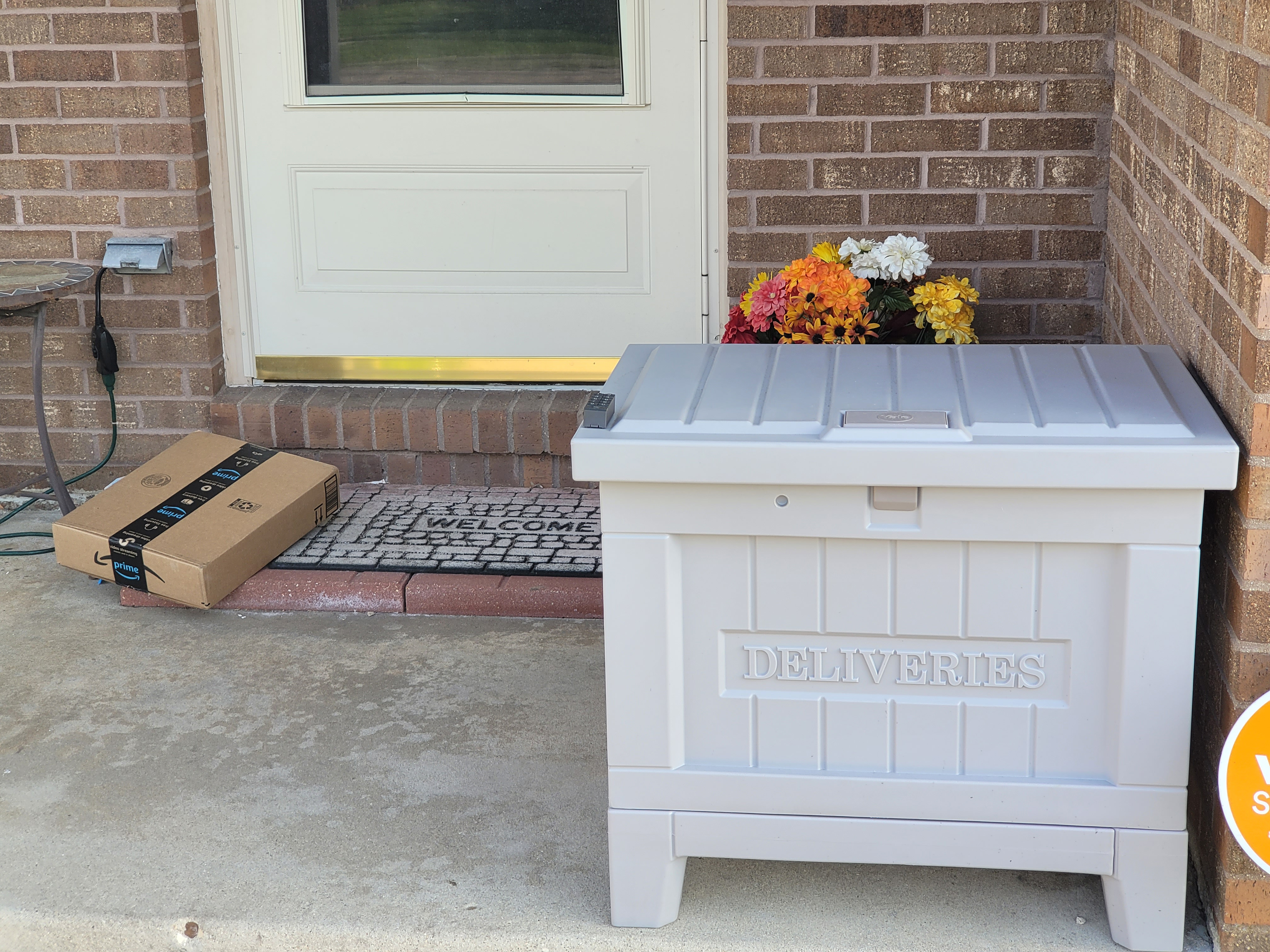 An Amazon package sits on the front porch near the Yale Smart Delivery box,.