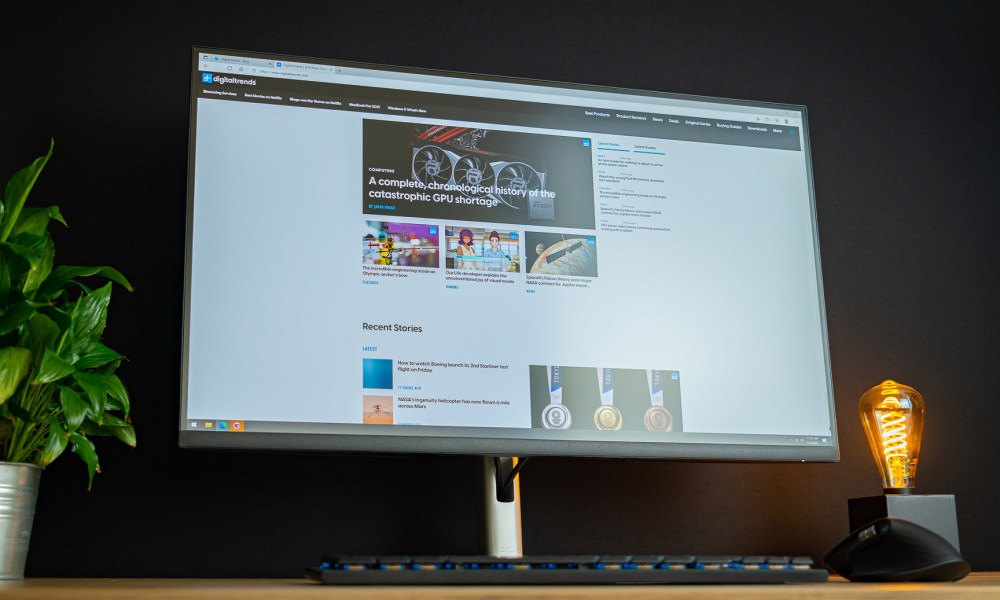 Dell 32 4K USB-C Hub monitor sitting on desk next to plant and light.