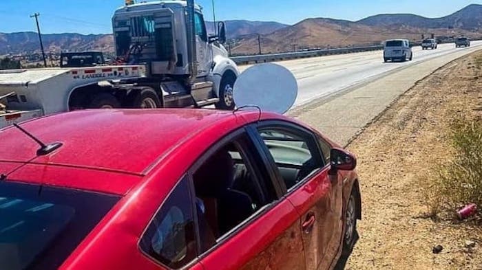 A satellite dish bolted to a car's hood.