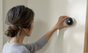 Photo of a woman adjusting a Nest Thermostat.