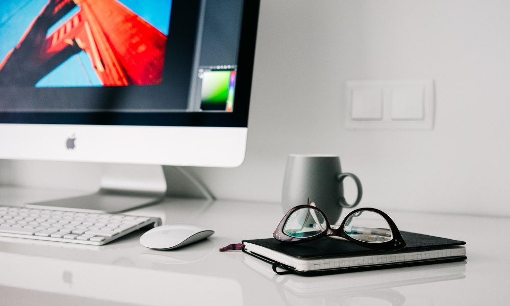 iMac on a desk with glasses and a notebook from Pixabay.