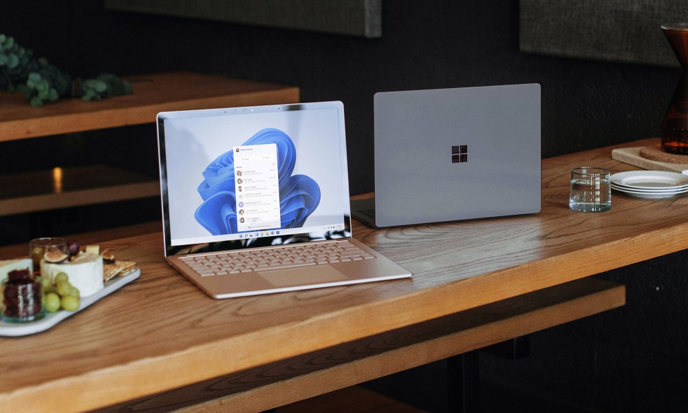 Two windows laptops sit on a wooden table.