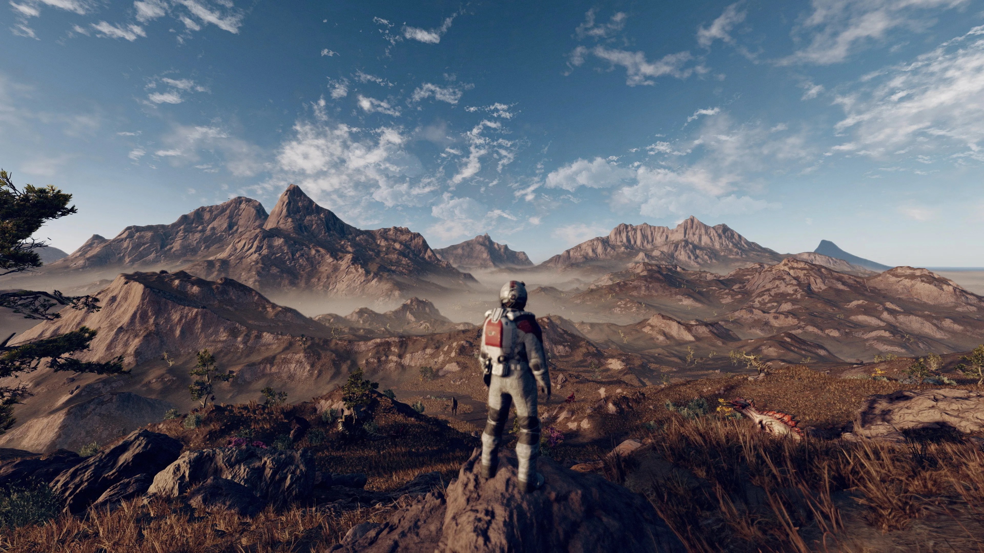 A space explorer stands in front of a mountain range in Starfield.