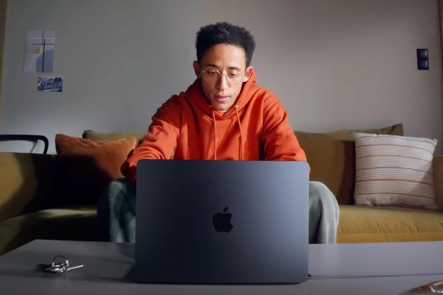 A man sits at his couch using the M2 Macbook Air.