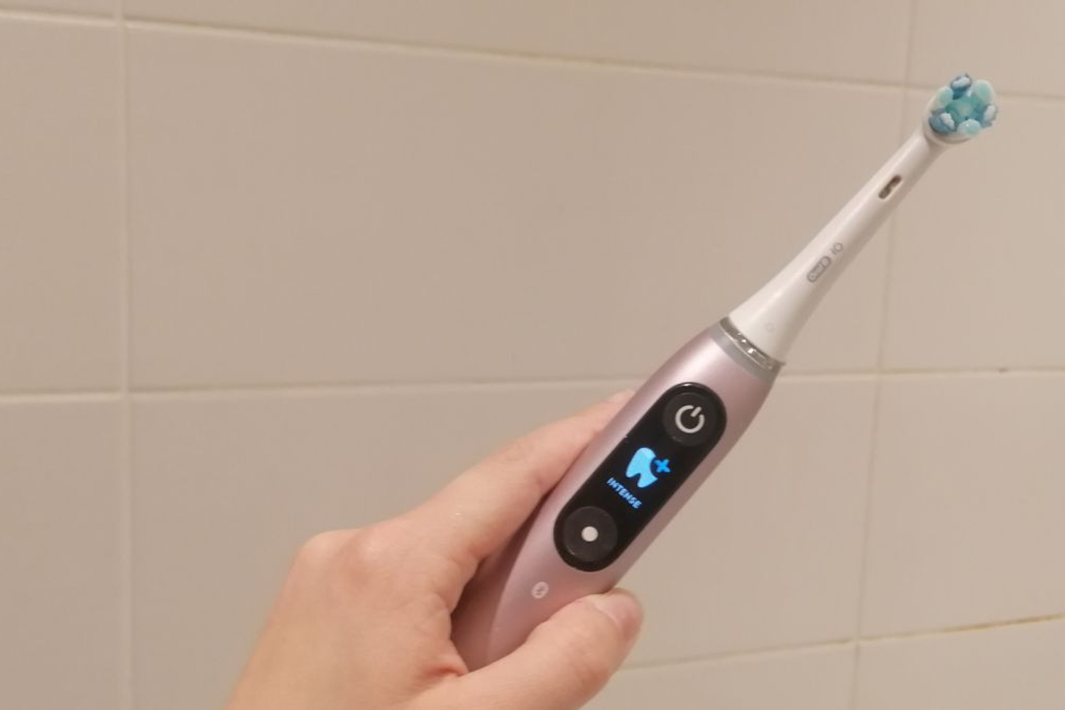 Close up of hand holding Oral-B iO Series 9 electric toothbrush.