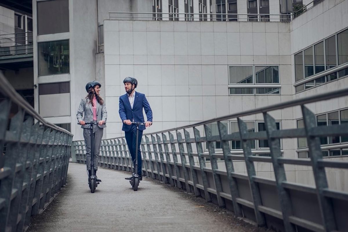 A man and woman ride their Segway Ninebot KickScooter Maxes through the city.