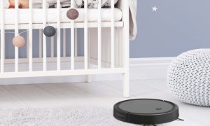 The ionvac SmartClean 2000 robot vacuum vacuums the floor of a nursery while a baby lies asleep in its crib.