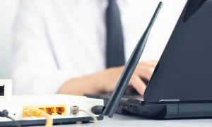 A Wi-Fi router next to a laptop.