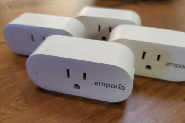 Four Emporia Smart Plugs displayed on a wooden table.