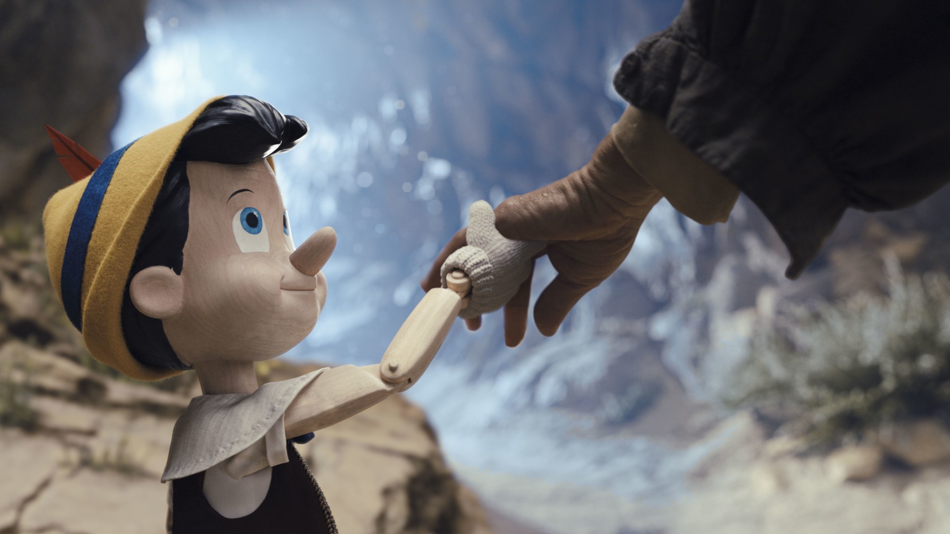 Pinocchio holds Geppetto's hand in a scene from the 2022 live-action film.