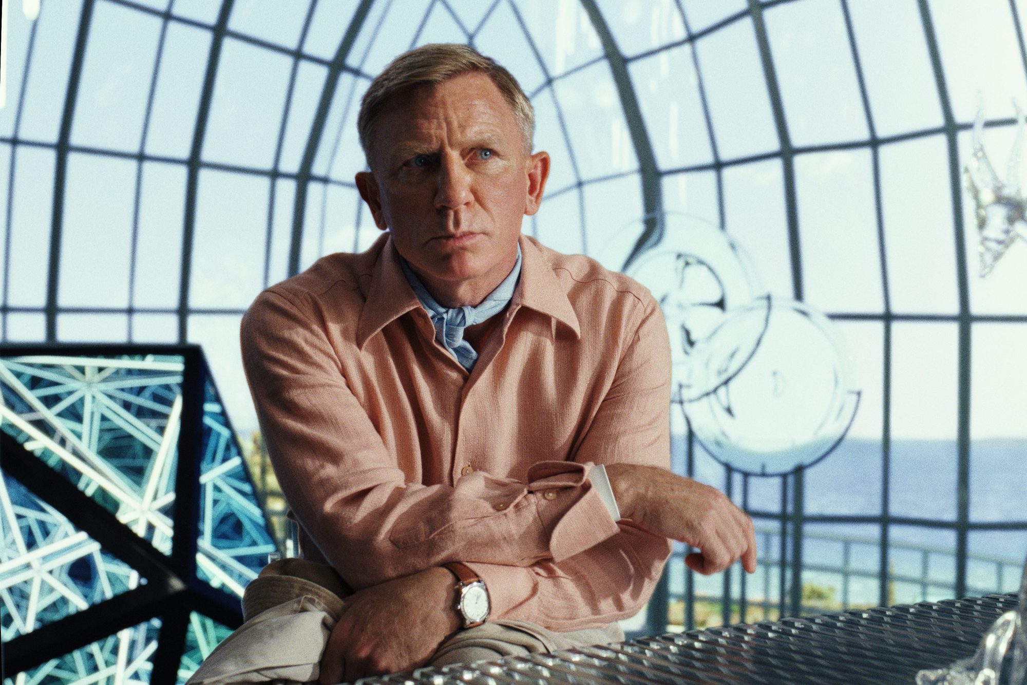 Daniel Craig stands and ponders in a scene from Glass Onion: A Knives Out Mystery.