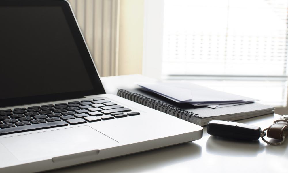 MacBook with a notebook and keys on a desk.