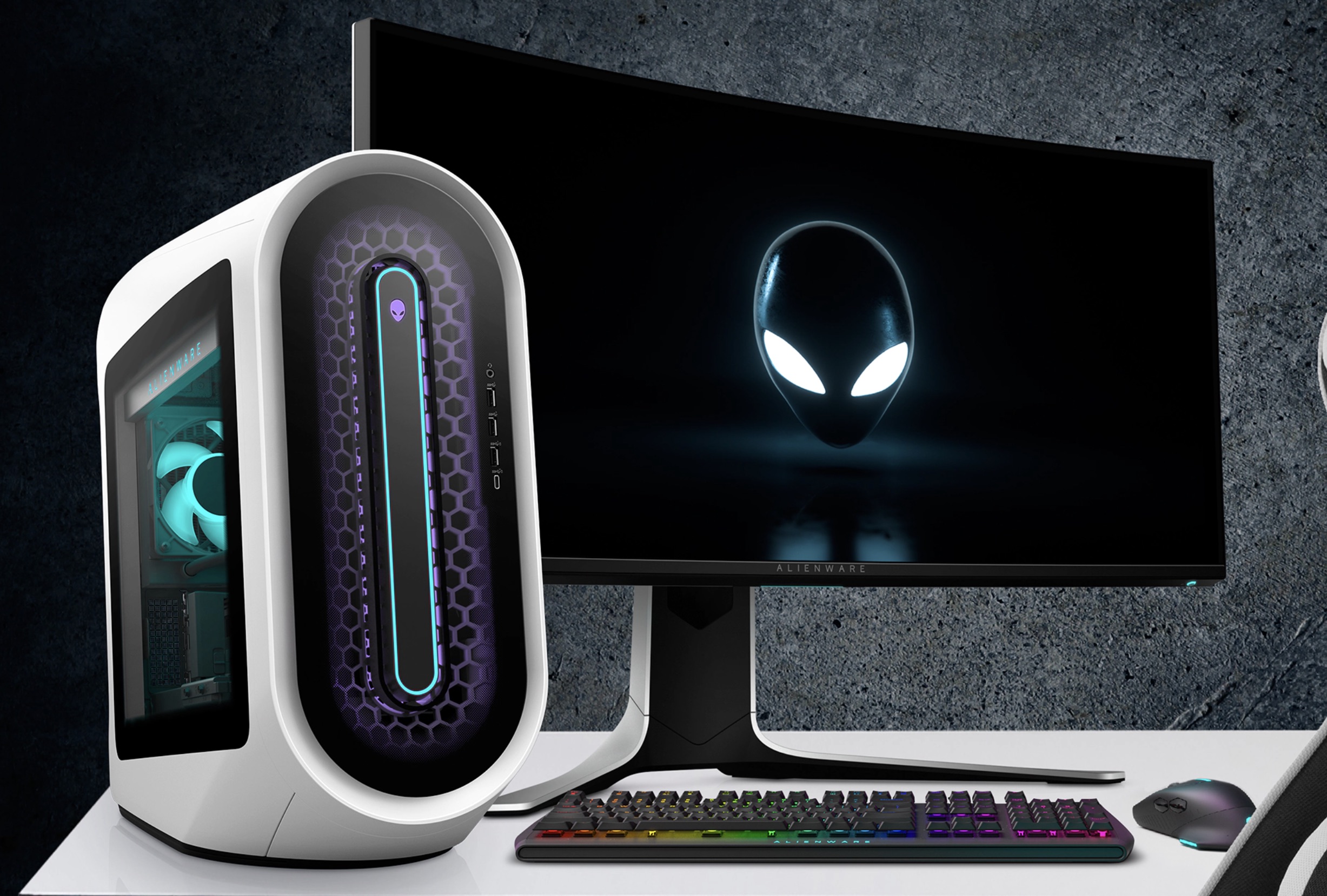 The Alienware Aurora R13 gaming desktop on a desk next to a monitor.