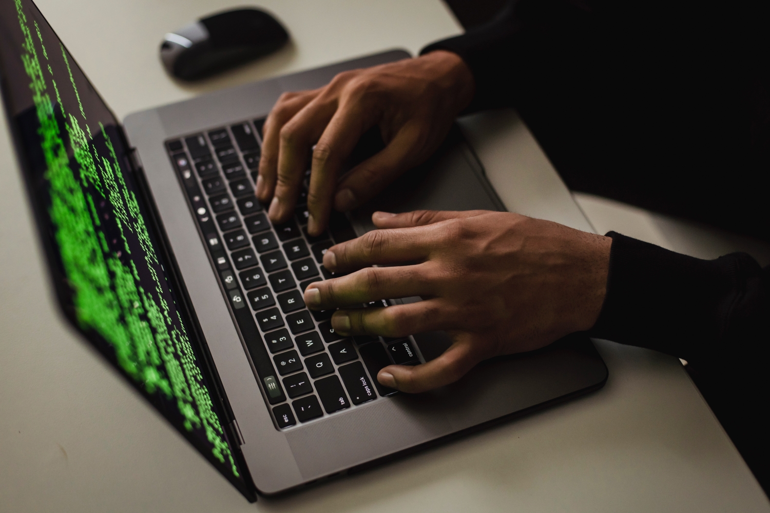 A person using a laptop with a set of code seen on the display.