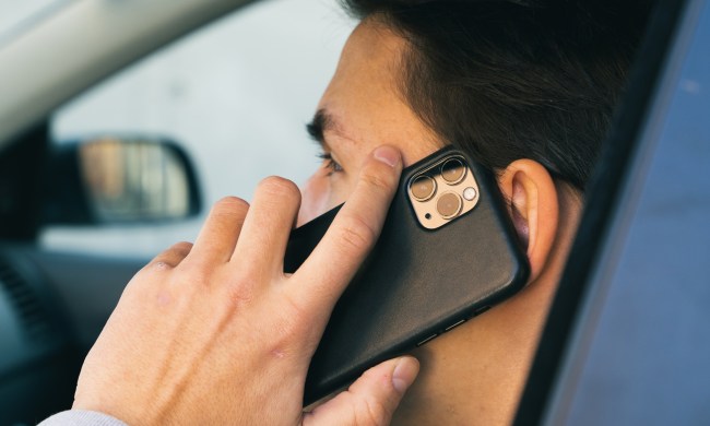 Side profile of a person in a car holding an iPhone to their ear.