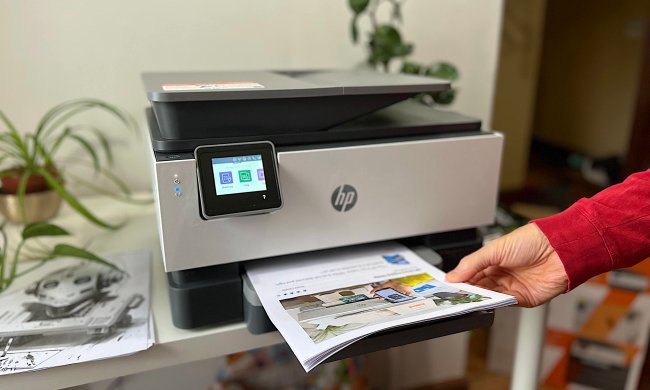 Lifting a stack of documents from the HP OfficeJet Pro 9015e's paper tray.