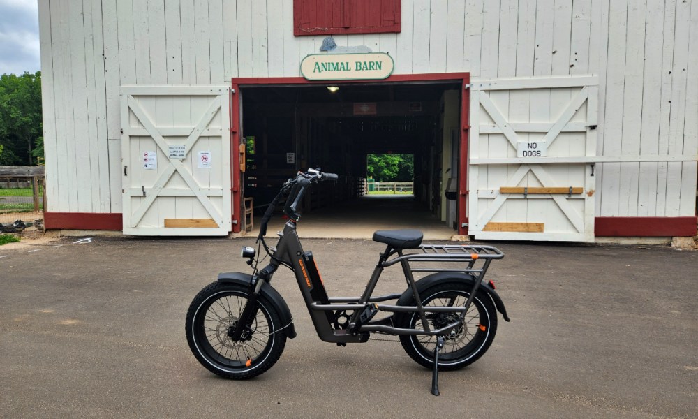 Rad Power Bikes RadRunner 3 Plus parked in front of an animal barn in a park.