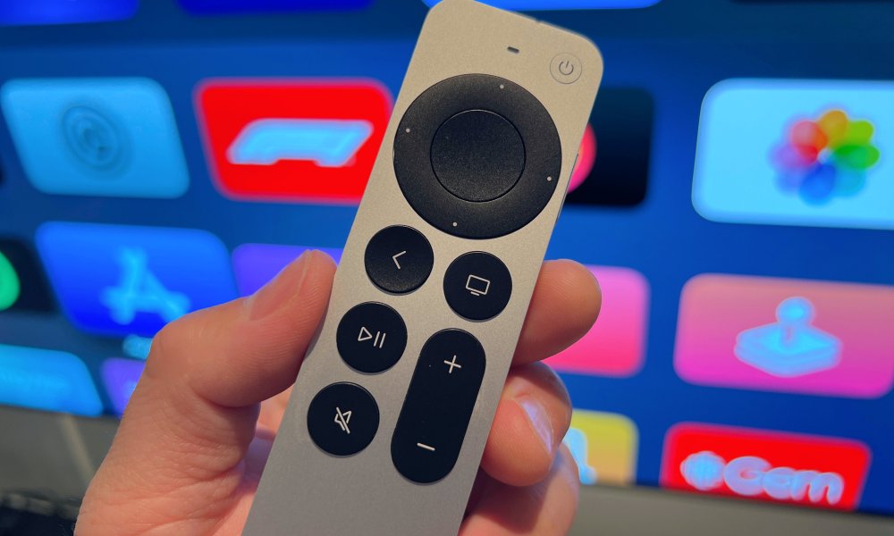 A person holding the Apple TV remote infront of a screen.