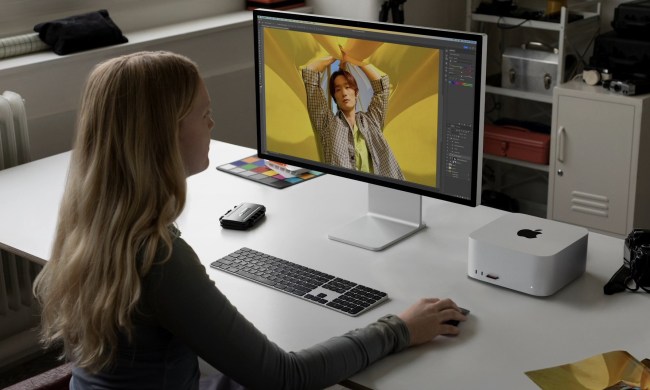 A woman sits at a desk with the M2 Mac Studio on it.