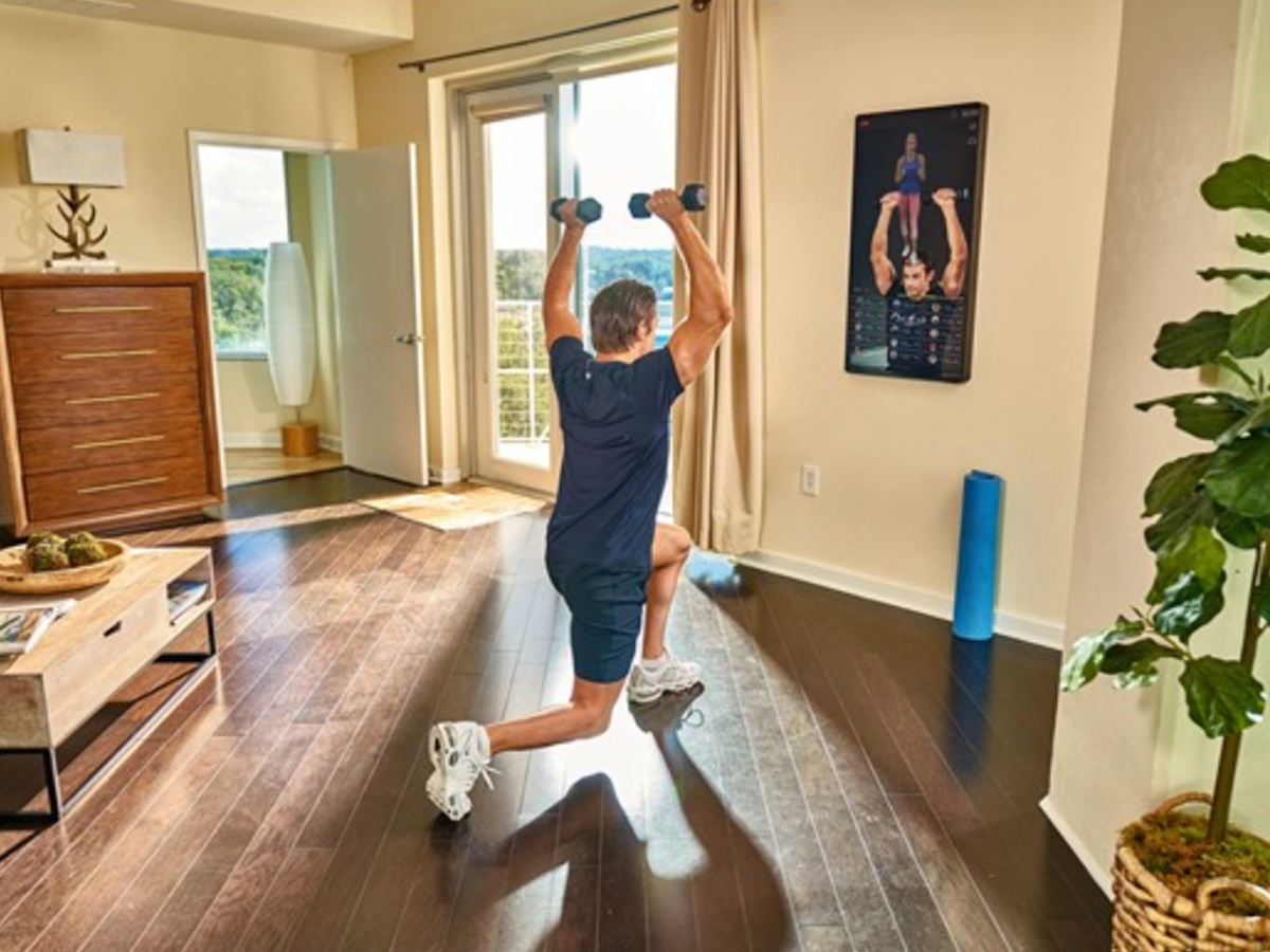 A man works out at home in front of an Echelon Reflect smart workout mirror.