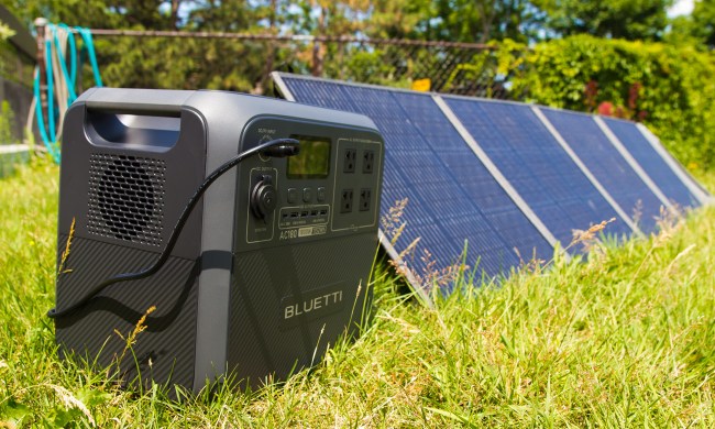 The Bluetti AC180 power station connecting to solar panels on a lawn.