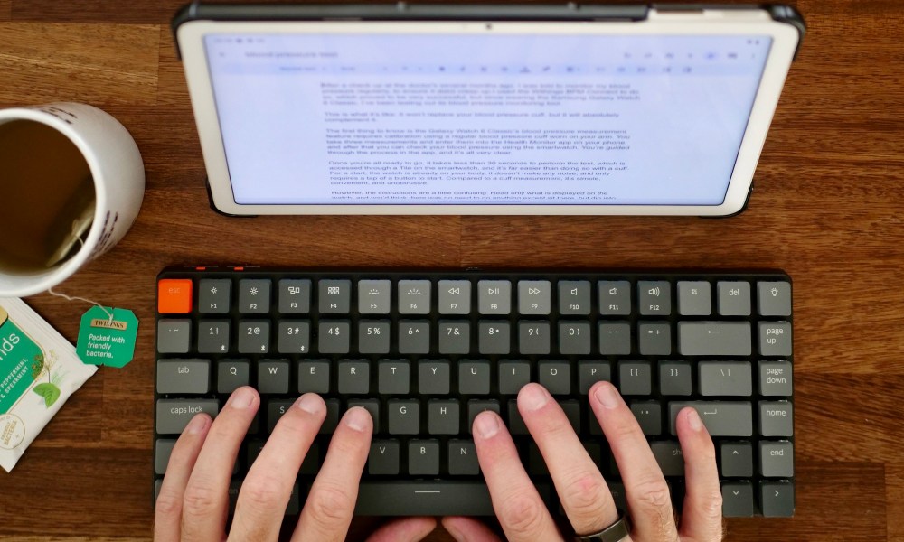 A person typing on a keyboard, connected to a Pixel Tablet.