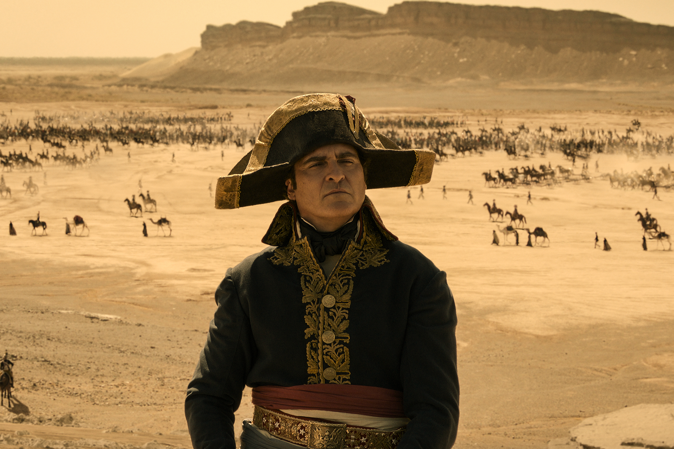 Joaquin Phoenix sits near a battlefield in Napoleon.