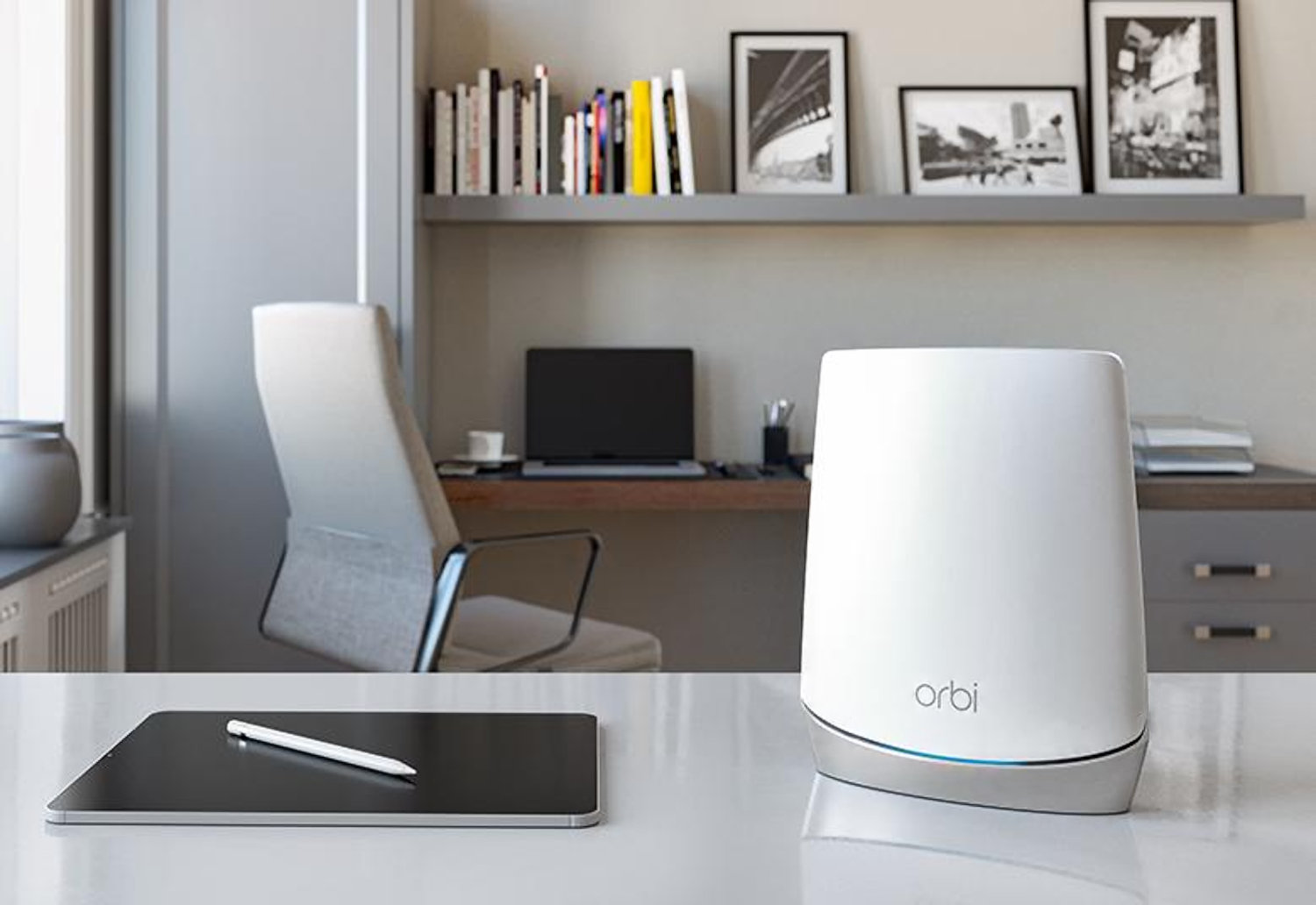 best modem router combo netgear s orbi cbr750 sits on a table beside an ipad  with laptop is in the background