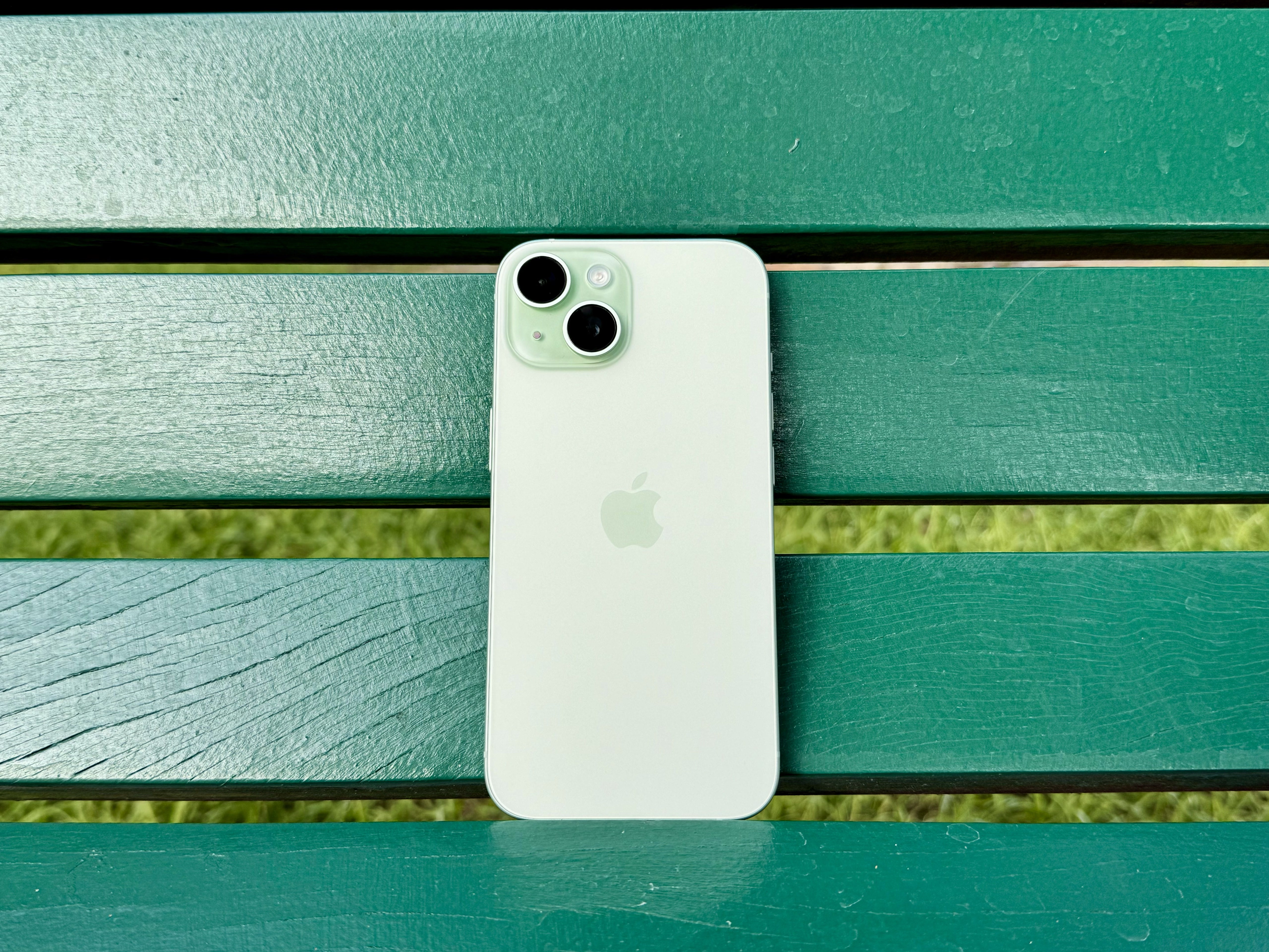 A green iPhone 15 on a green bench.