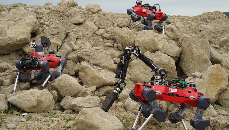 A team of legged rovers explores a rugged surface.