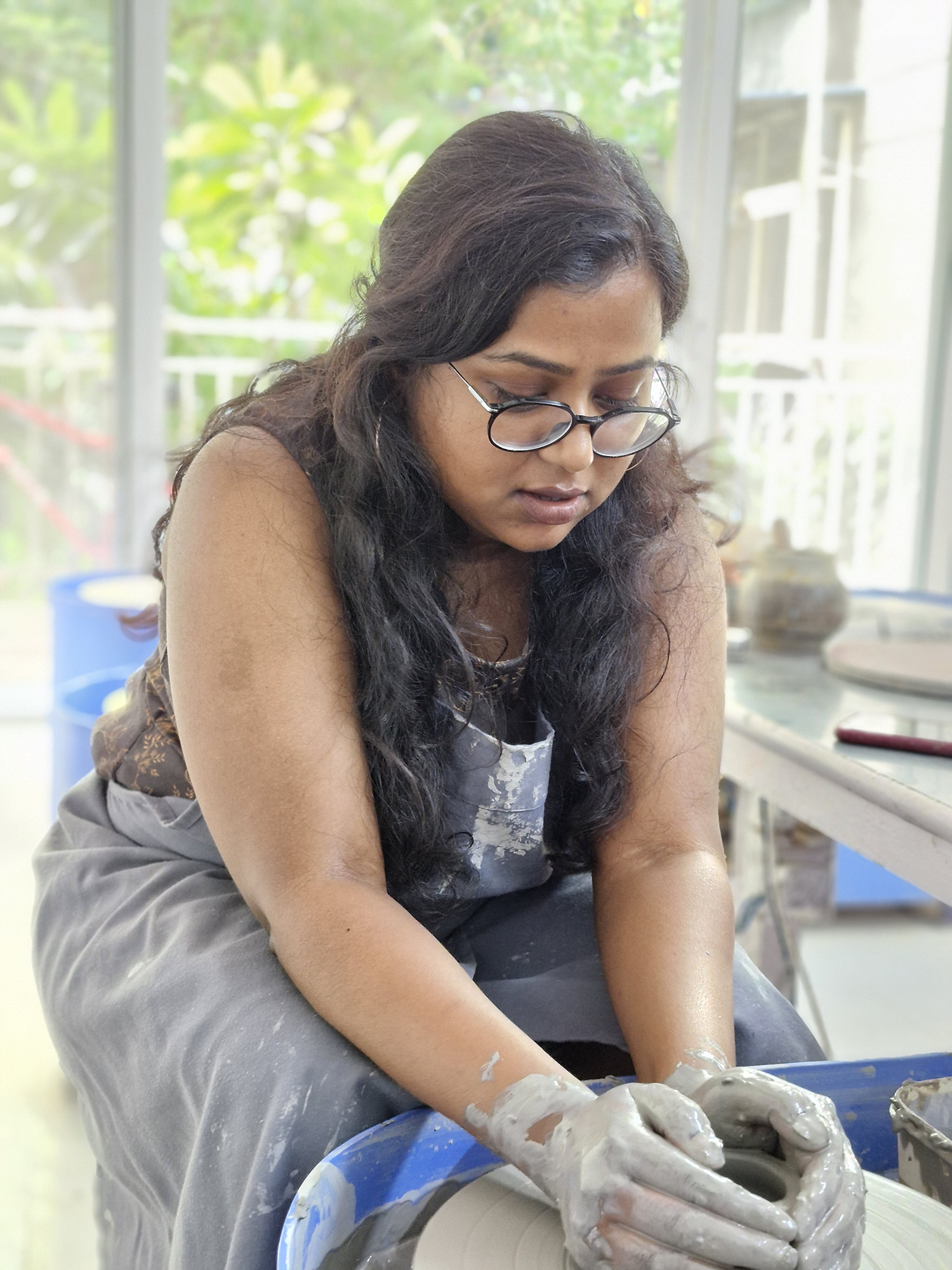 Portrait of a lady using the potters' wheel photographed with the Samsung Galaxy S23 FE.