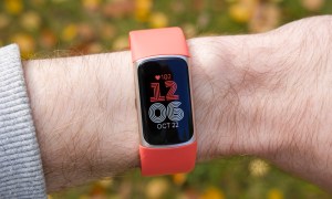 Someone wearing a Fitbit Charge 6 with a coral band.