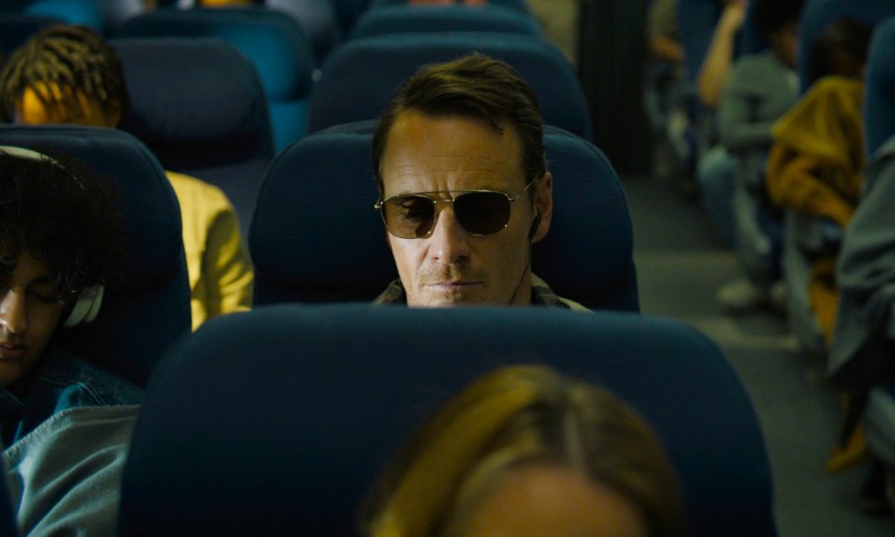 A man sits on a plane in The Killer.