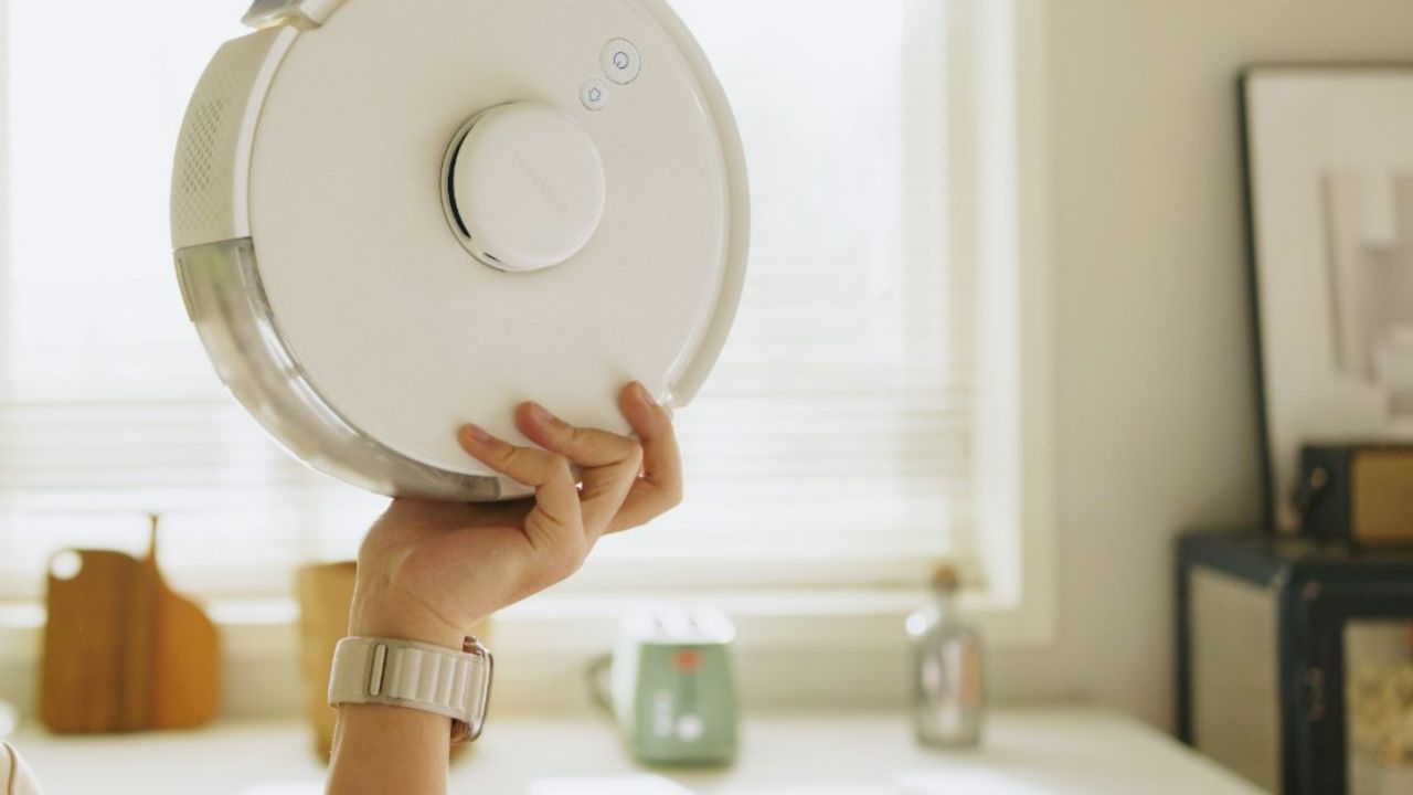 A person holding the SwitchBot K10+ robot vacuum.