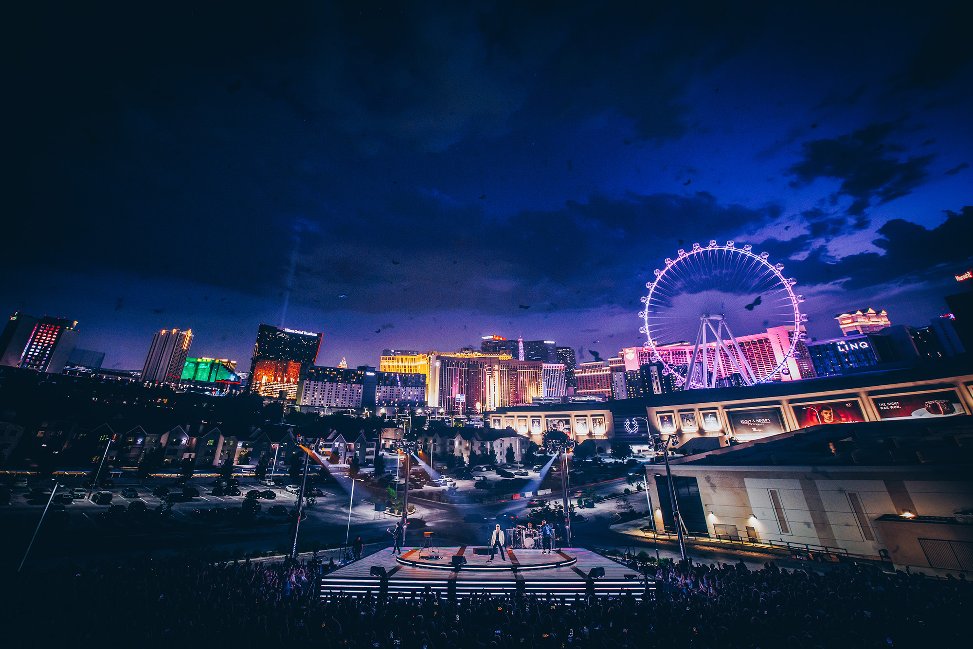 The Las Vegas strip lights up the background inside the Sphere as U2 plays on stage.